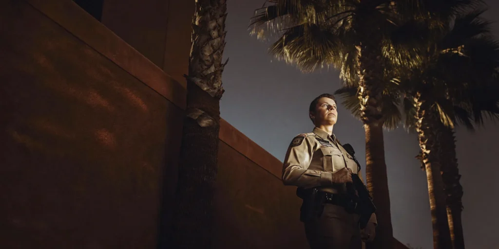 Professional armed security guard standing watch outside an Orange County office building at dusk