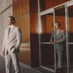 Professional executive protection officer standing discreetly beside a business leader outside a modern San Diego corporate building