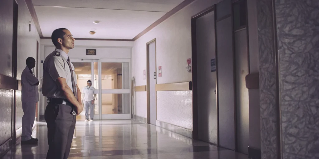 Professional security guard monitoring a hospital hallway near an emergency room entrance